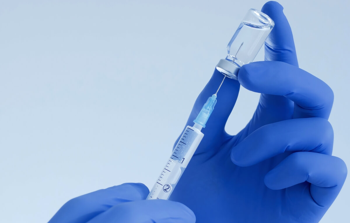 Image of two hands holding a needle with vaccine
