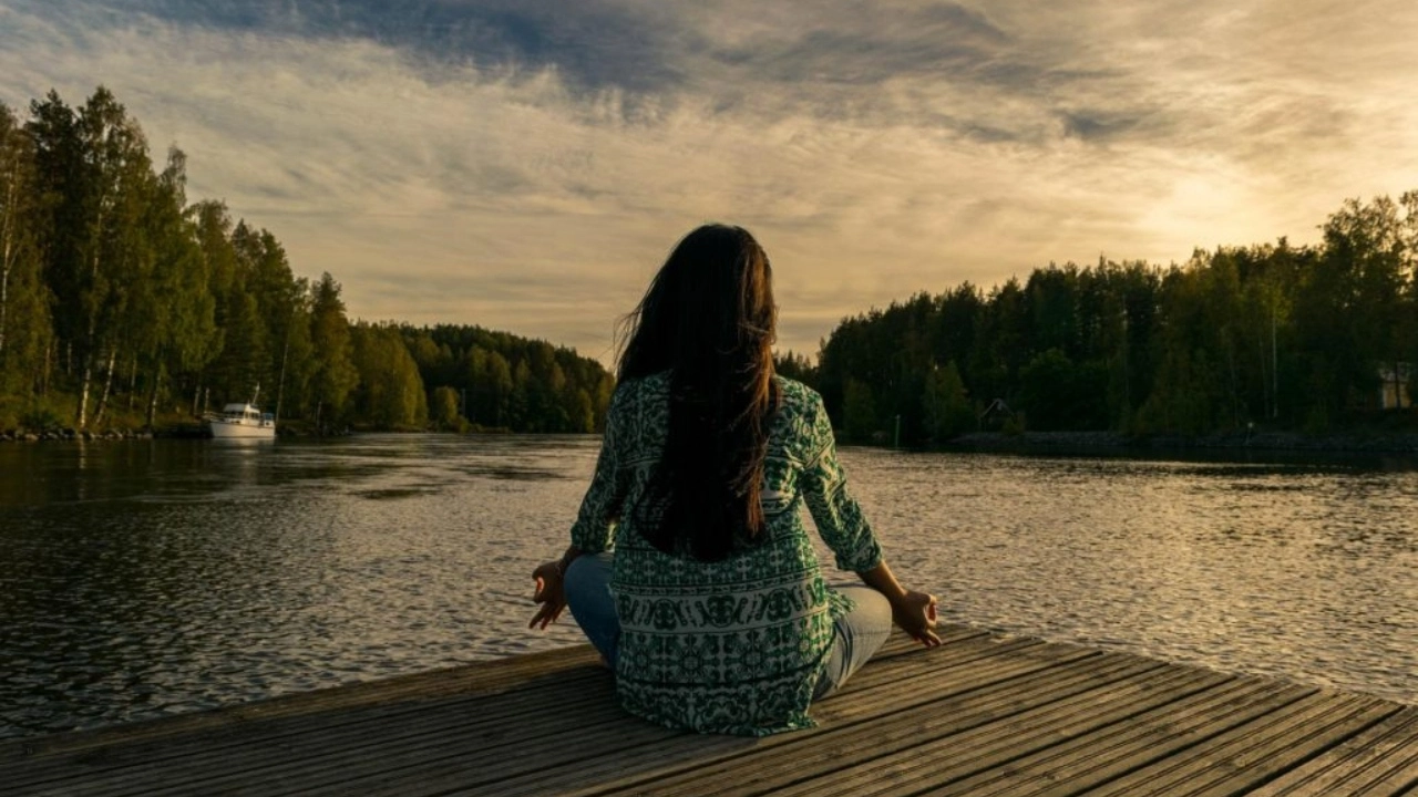 Image of a woman meditating on a dock with a boat in her line of sight