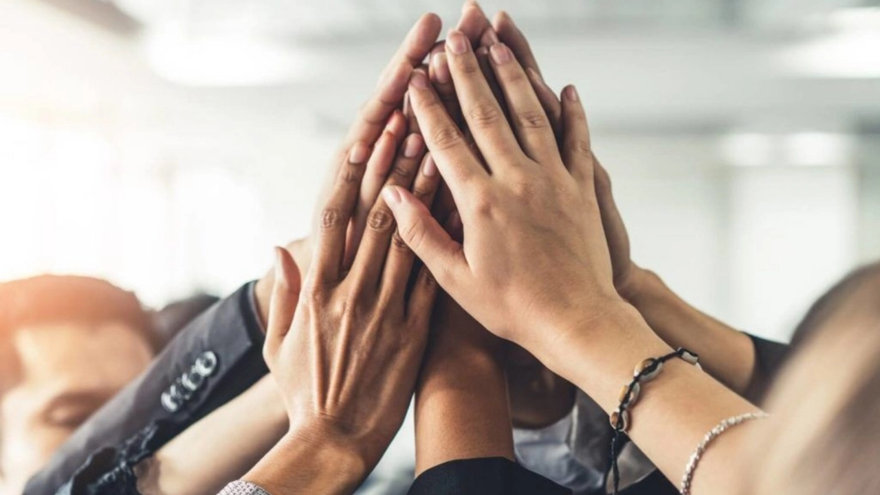 Image of diverse group of co-workers raising hands together