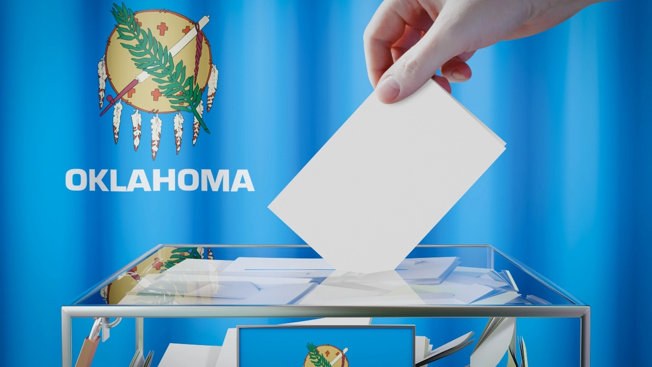 Image of a female hand depositing a ballot in front of an Oklahoma state flag