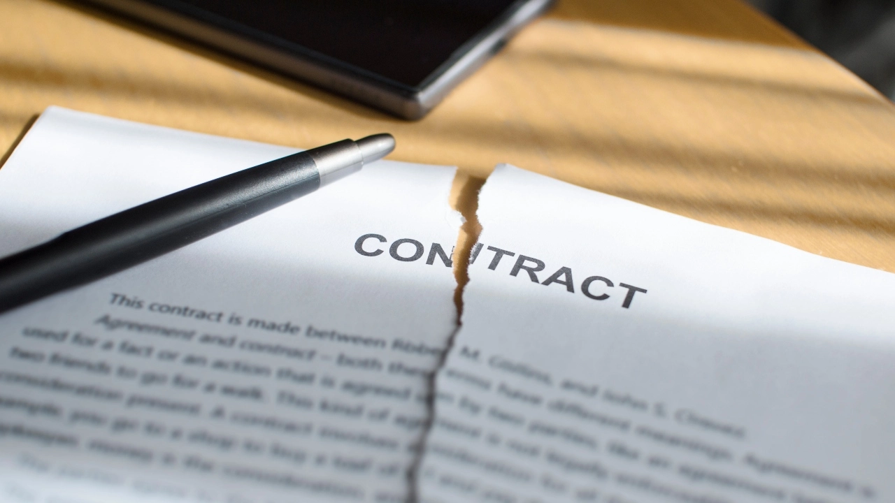 Image of a pen sitting atop a contract that is torn in two from the top