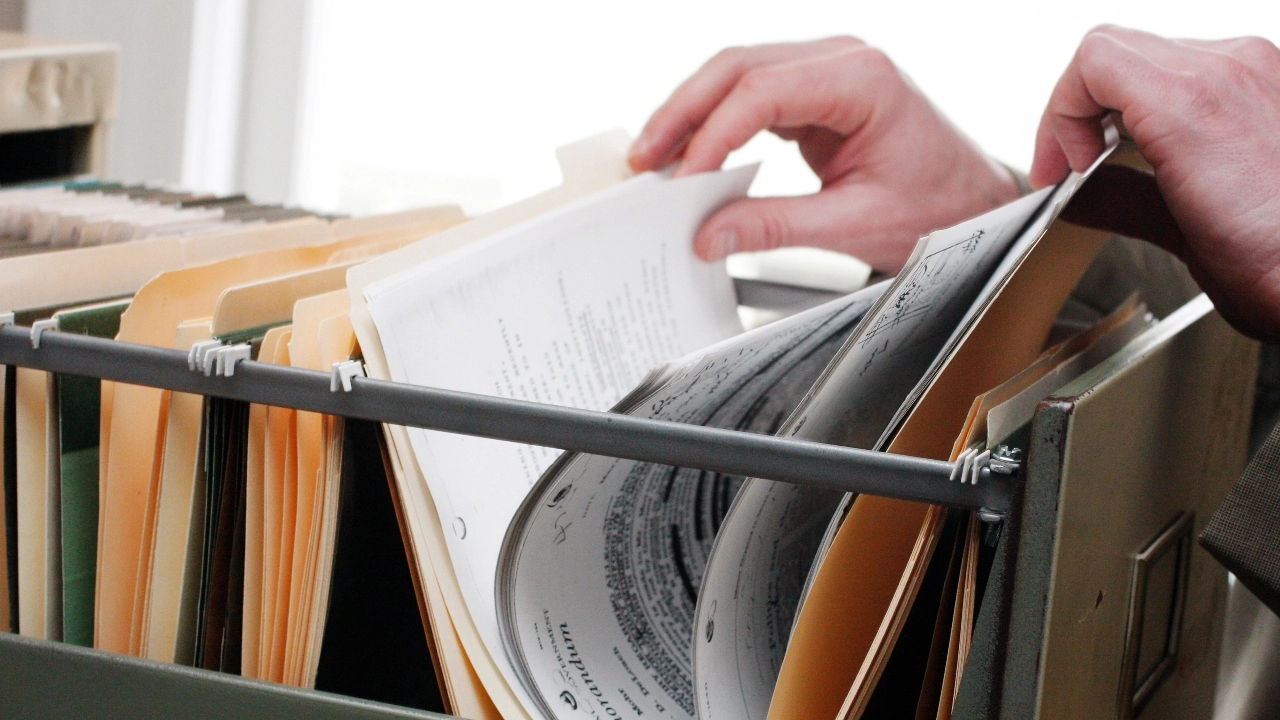 Image of a person's hands looking through a drawer of file folders