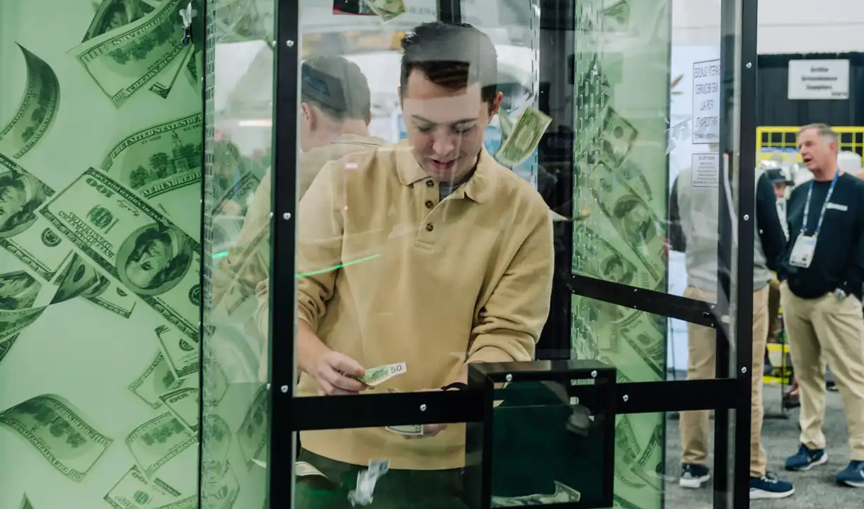Image of man grabbing cash inside Green Rebates' money booth at MJBizCon on Friday, Dec. 6.